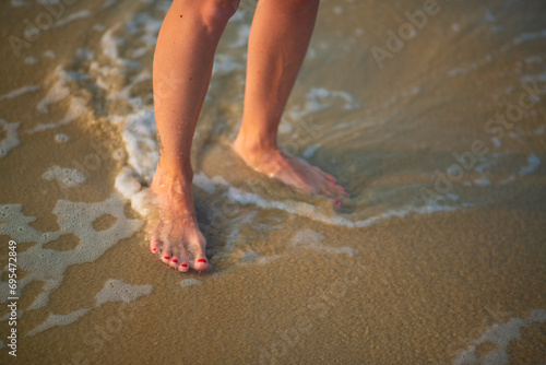female feet on the sandy shore washed by the sea