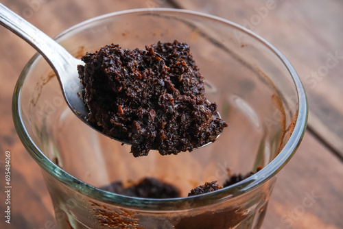 Someone scoops out coffee grounds that have settled at the bottom of a cup or glass. Waste from coffee drinks. photo