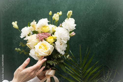 Floristry. Flowers. A florist girl collects a bouquet of white and yellow roses. Blurred background.