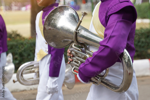 Students carry mellophones in the school orchestra procession It is a medium-pitched brass instrument used in marching bands and is used to play the French horn section in bands and orchestras. photo