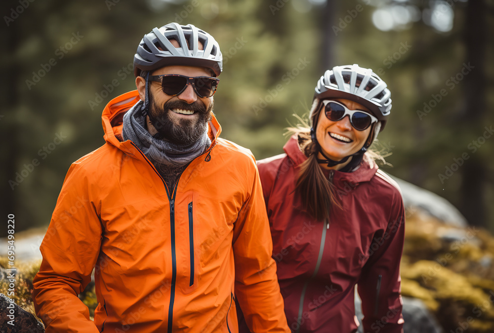 Man & woman in cycling helmets, smiling in green field Man & woman in cycling helmets, smiling in green field