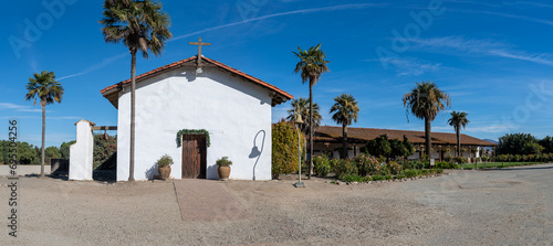 Old church with bell on the side palm trees  and flower garden