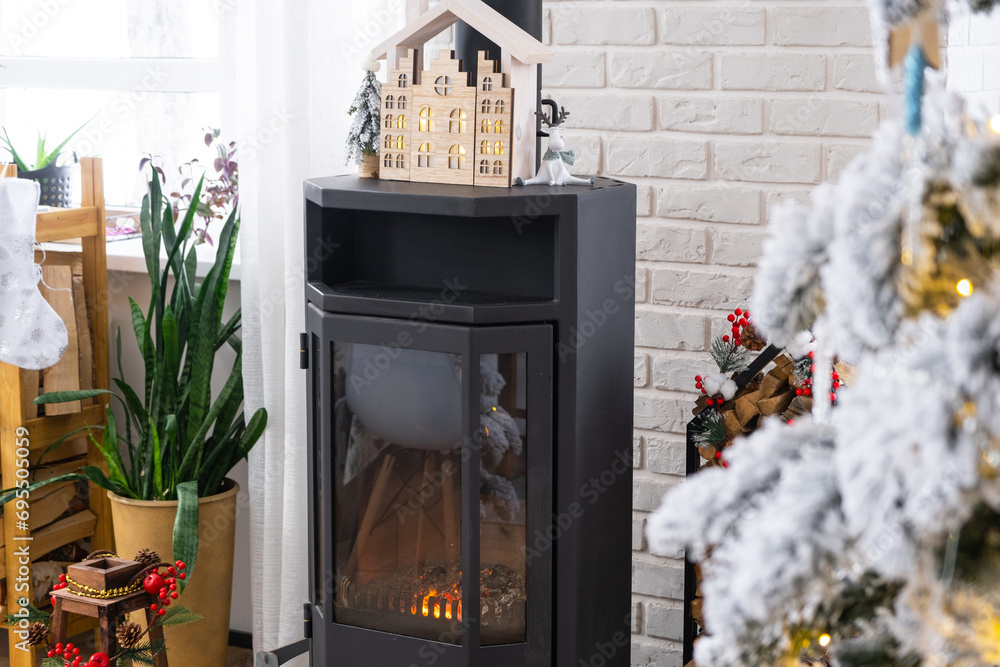 Φωτογραφία Metall black stove, burning hearth fireplace in white Festive interior of house is decorated for Christmas and New Year, Christmas tree