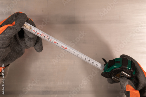 Gloved hand holding a measure tape isolated