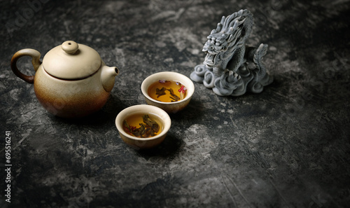 clay teapot, tea cups and dragon figurine on dark table abstract background. Asian culture cuisine concept. tea ceremony in Japanese or chinese style