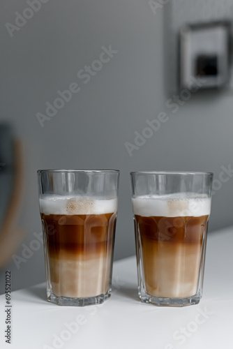 Set with two tall glasses of hot aromatic espresso coffee with cream poured over on gray background. Banner design. 