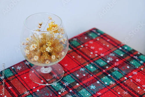 Dried grass in champagne glass on a corner of table with Christmas theme tablecloth