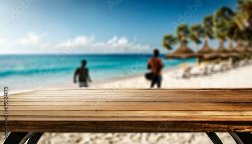 wood table top on blurred blue sea and white sand beach background with some people