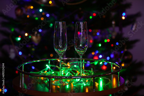 Two champagne glasses on background of green Christmas tree garland....