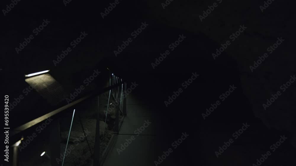 A dimly lit pathway through the depths of a cave, illuminated only by ...
