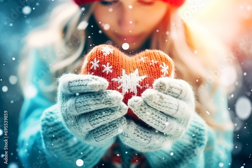 Female hands in mittens with knitted heart in snow winter. Valentines Day romantic concept photo