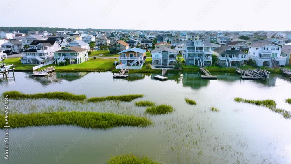 Aerial tracking shot of canal in front of beach homes and docks at ocean isle, nc.