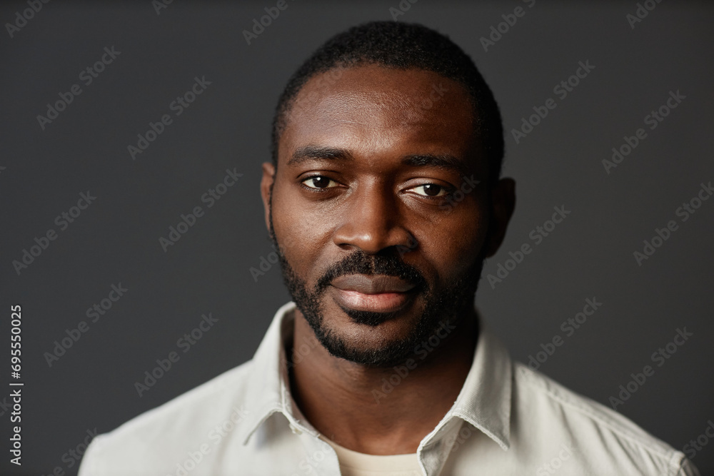 Fototapeta premium Front view portrait of successful African American man looking at camera against black background