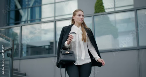 Pretty businesswoman walking down the stairs, leaving office building. 