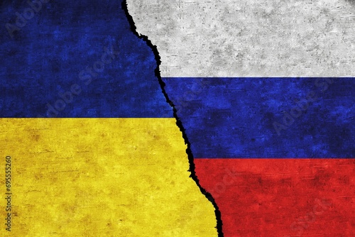 Concept of a conflict between Russia and Ukraine with painted flags on a wall with a crack