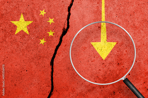 China flag painted on a cracked concrete background. China finance, real estate and debt crisis. China economic collapse. View through magnifying glass