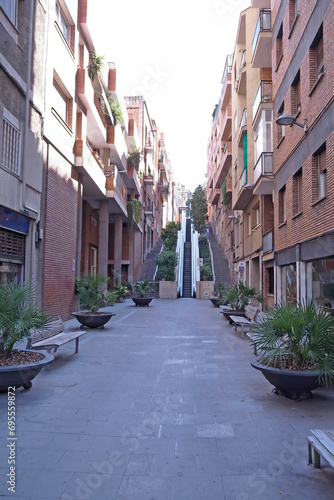 Fototapeta Naklejka Na Ścianę i Meble -  Urban Oasis: Calm Pedestrian Walkway with Escalators and Planters Spain
