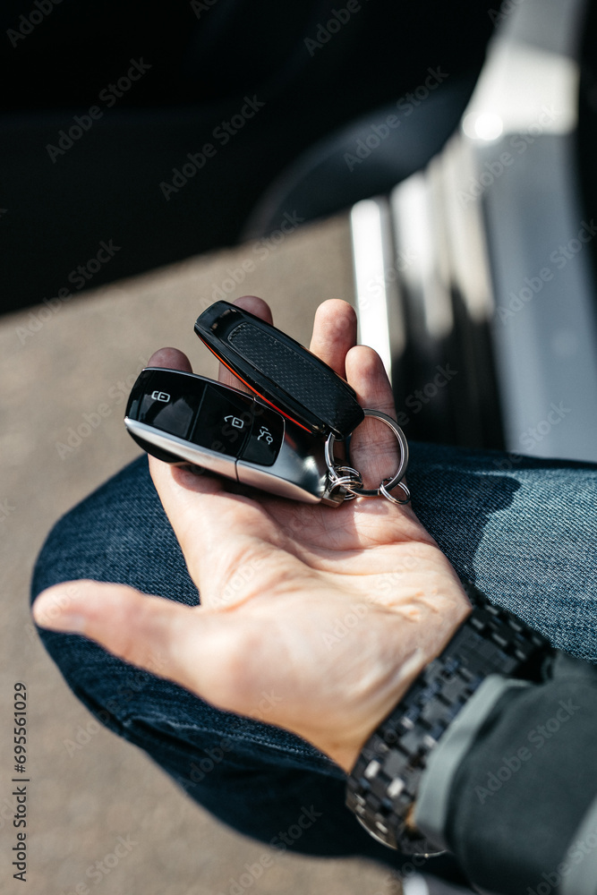 close-up vertical photo of a man holding the keys to an expensive suv in his hands