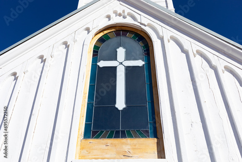 Wooden White Church Stained glass window with Cross, Blue Sky On Background. Christian Religious Holiday Easter or Radonitsa. Horizontal Plane photo