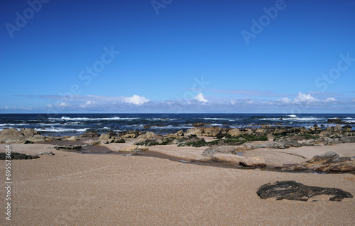 Landscape of a beach  ocean  sand rocks and sky with clouds  spring morning