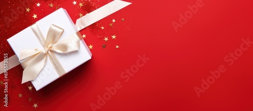 Top view one white gift box with red ribbon on red background.