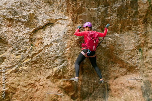 Back-view of a woman traversing horizontally along a rock wall