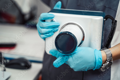 Dentist holds portable dental X-ray. Medical technology for teeth examination. Healthcare professional in dental clinic office. Radiology patient safety equipment. Oral diagnostics, checkup treatment