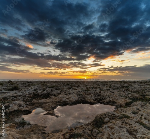 sunset on a rocky beach on the Gulf of Taranto in Apulia with a tidal pool in the foreground
