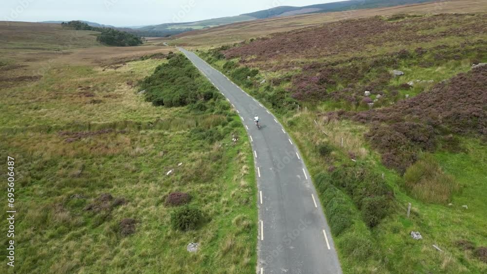 Cyclist riding a bicycle on a road in Wicklow mountains Ireland, aerial drone shot. Cyclist riding a bicycle on a road in Wicklow mountains Ireland, aerial drone shot.