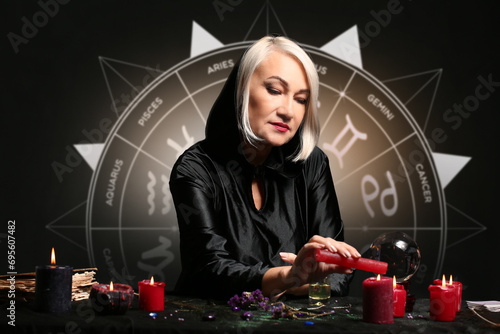 Female astrologer reading future on dark background photo