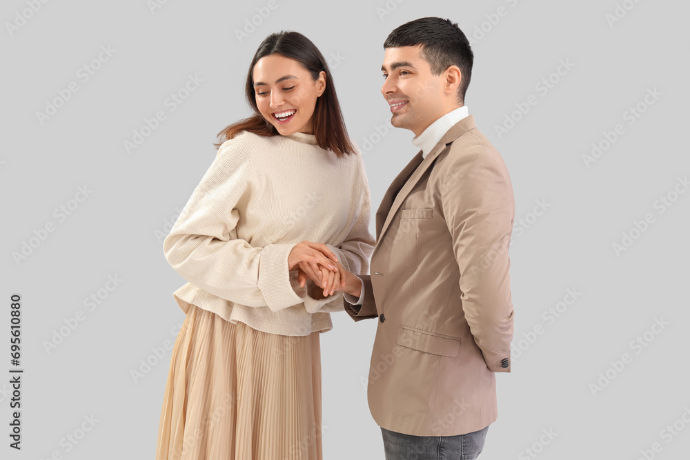 Lovely young couple holding hands on light background Lovely young couple holding hands on light background
