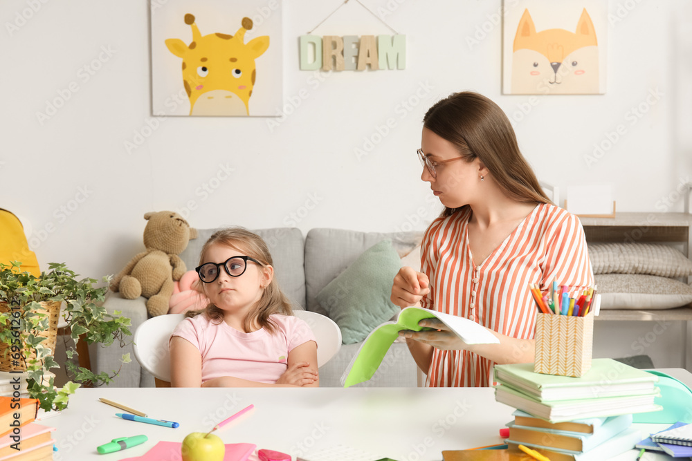 Upset little girl doing lessons with her mother at home Upset little girl doing lessons with her mother at home