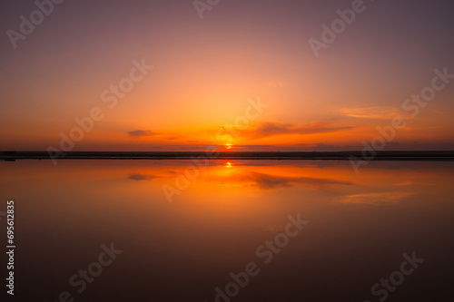 Sunset or sunrise sky. Clouds over water. Golden Dawn. Dramatic coast nature background. Beautiful sea beach at sunset. Morning shoreline sunlight. 