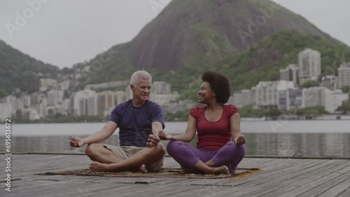 Casal de meia idade meditando sentada em um pier de frente para o mar. Cinematico 4k. photo