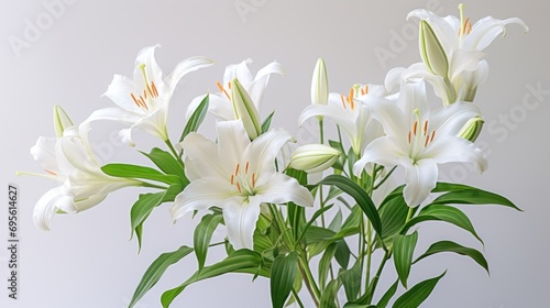  a vase filled with white lilies on top of a wooden table and a white wall in the back ground.