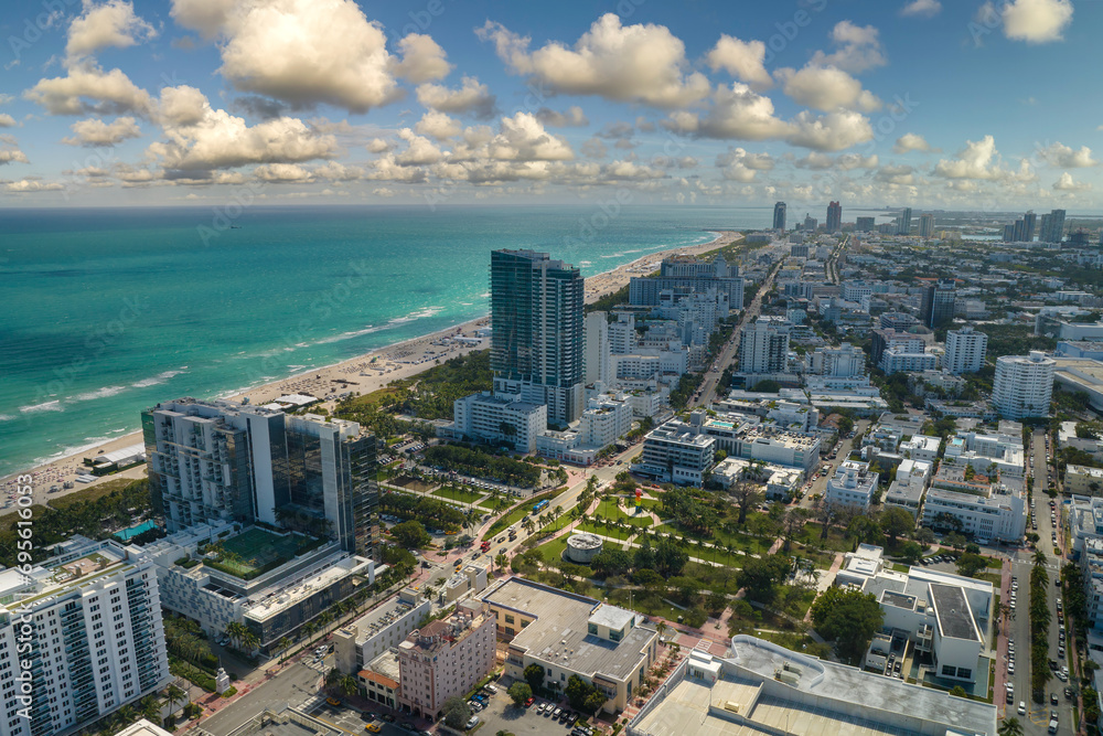 Travel destination in United States. South Beach sandy surface with tourists relaxing on hot Florida sun. Tourism infrastructure in southern USA. Miami Beach city with high luxury hotels and condos - obrazy, fototapety, plakaty 