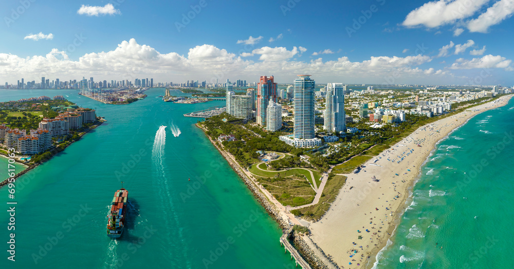 Naklejka premium View from above of big container ship entering main channel in Miami harbor near South Beach high luxurious hotels and apartment buildings