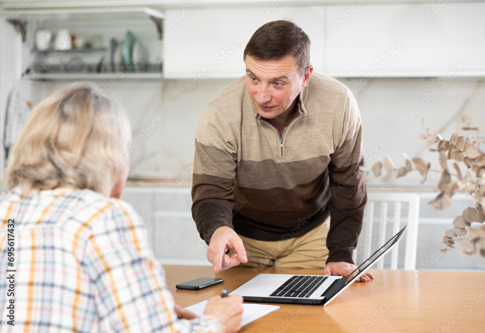 Obraz premium Male financial agent tells an elderly woman the terms of microloan. Offers to sign documents