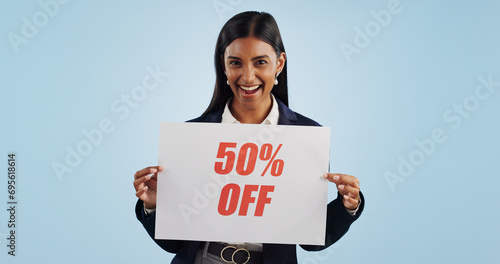 Fotografie Happy woman, portrait and sign for advertising discount, deal or half price against a blue studio background