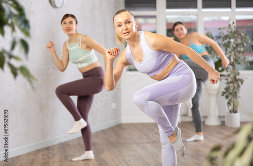Positive women doing aerobics exercises in gym area during workout session