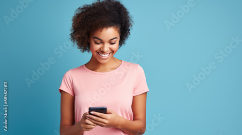 Young woman smiling and holding her smartphone on a blue background
