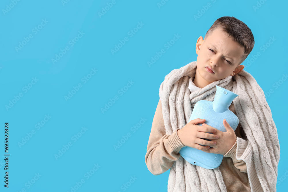 Ill little boy with scarf and hot water bottle on blue background Ill little boy with scarf and hot water bottle on blue background