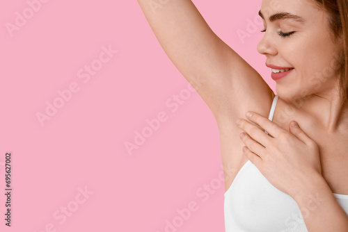 Beautiful young happy woman after epilation of armpit on pink background photo