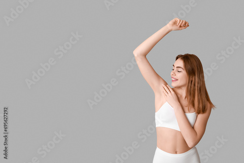 Beautiful young woman after depilation armpit on grey background photo