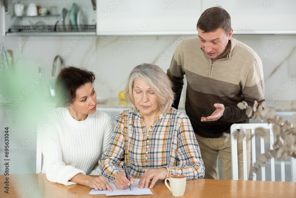 Fototapeta premium Old woman deciding and signing inheritance papers in family circle