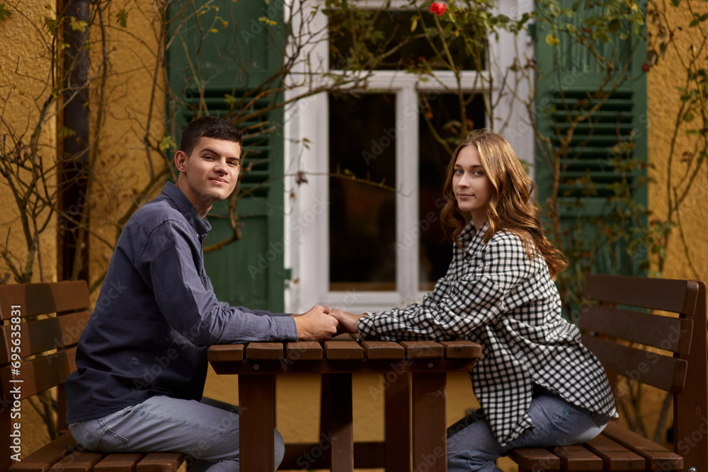 Teen Sweethearts: Holding Hands at an Outdoor Café in a European Town