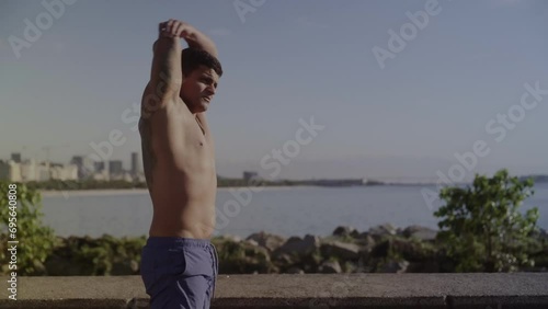 Homem jovem se alongando ao ar livre em frente ao mar. Cinematico 4k. photo