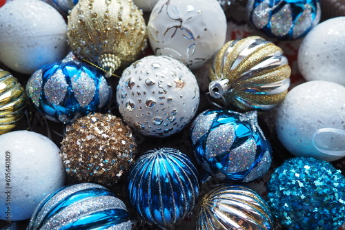 New Year's Christmas balls and decorations close up. A lot of decoration of golden, blue, yellow, white, silver. Striped Christmas balls lie on surface. Festive beautiful colorful background. Design.