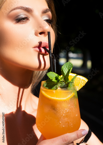 Beautiful woman with blue eyes hold fresh cold beverage in restaurant, close up. Sexy lady drink cocktait. Sensual girl Female enjoys a summer drink. Alcoholic drinks, fruit cocktail. photo