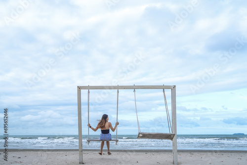 Portrait beautiful young asian woman relax smile leisure on swing around beach sea ocean with blue sky white cloud